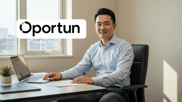 A man in a blue shirt smiling while sitting at a desk with a laptop, papers, and a small plant. The Oportun logo appears on the top left of the image.