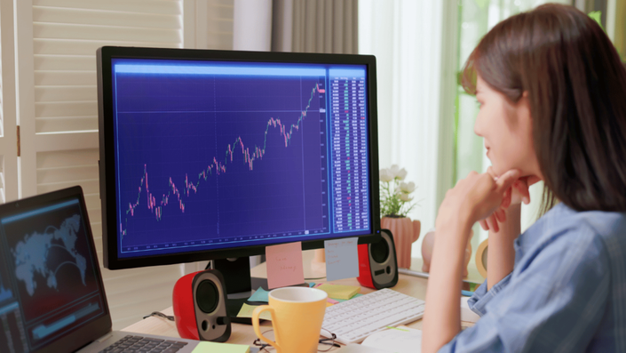 A woman analyzing stock market charts on a computer, focusing on investment growth and Tax Efficiency strategies.